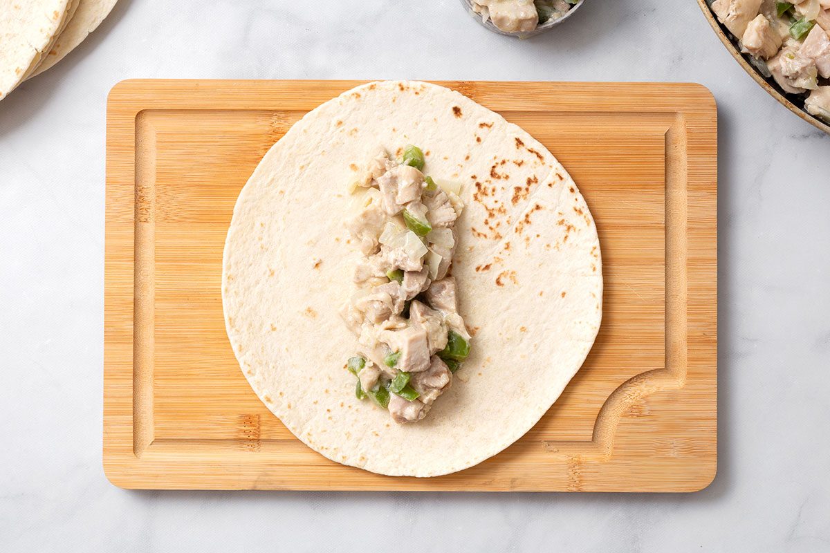 Flat flour tortilla with 1/2 cup of chicken filling before being rolled up for enchiladas