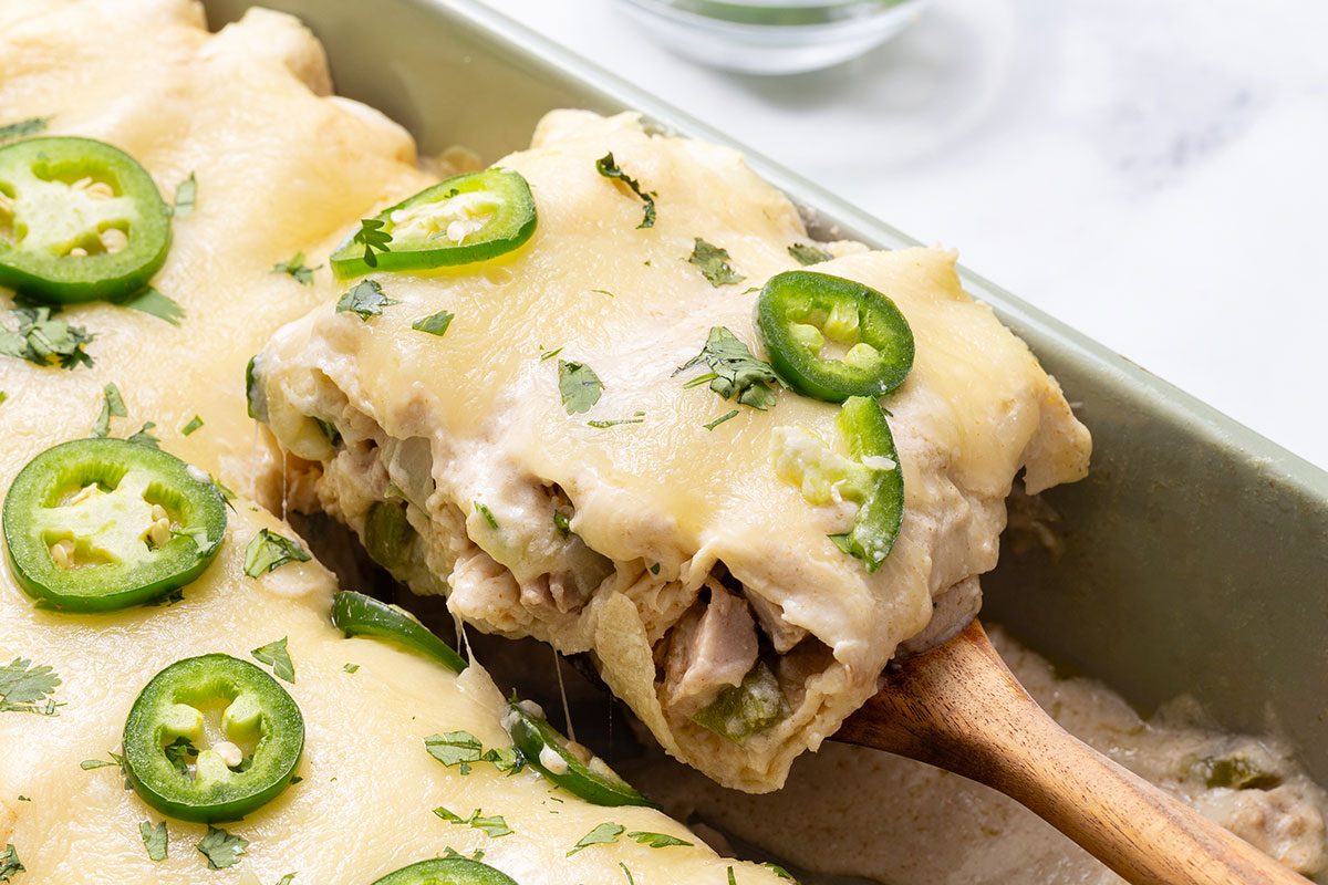 White Chicken Enchilada slice being taken out of baking dish