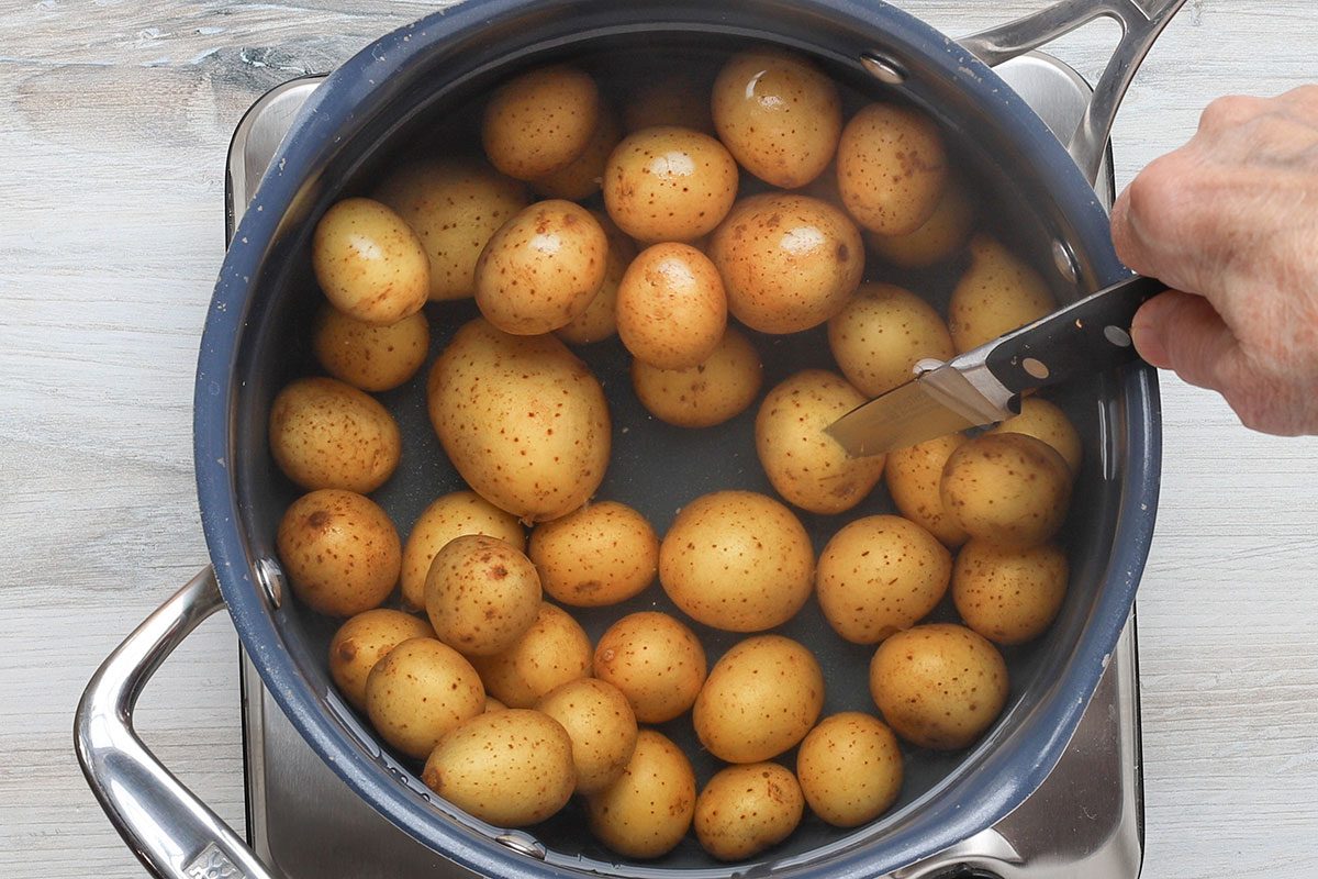 Testing the potatoes with a paring knife to make air fryer smashed potatoes.