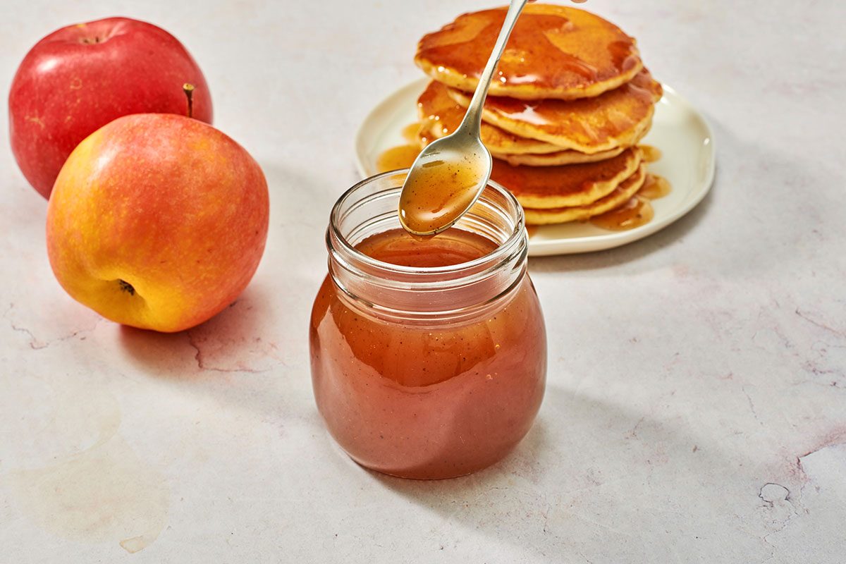 Syrup in a jar with a stack of pancakes in the background