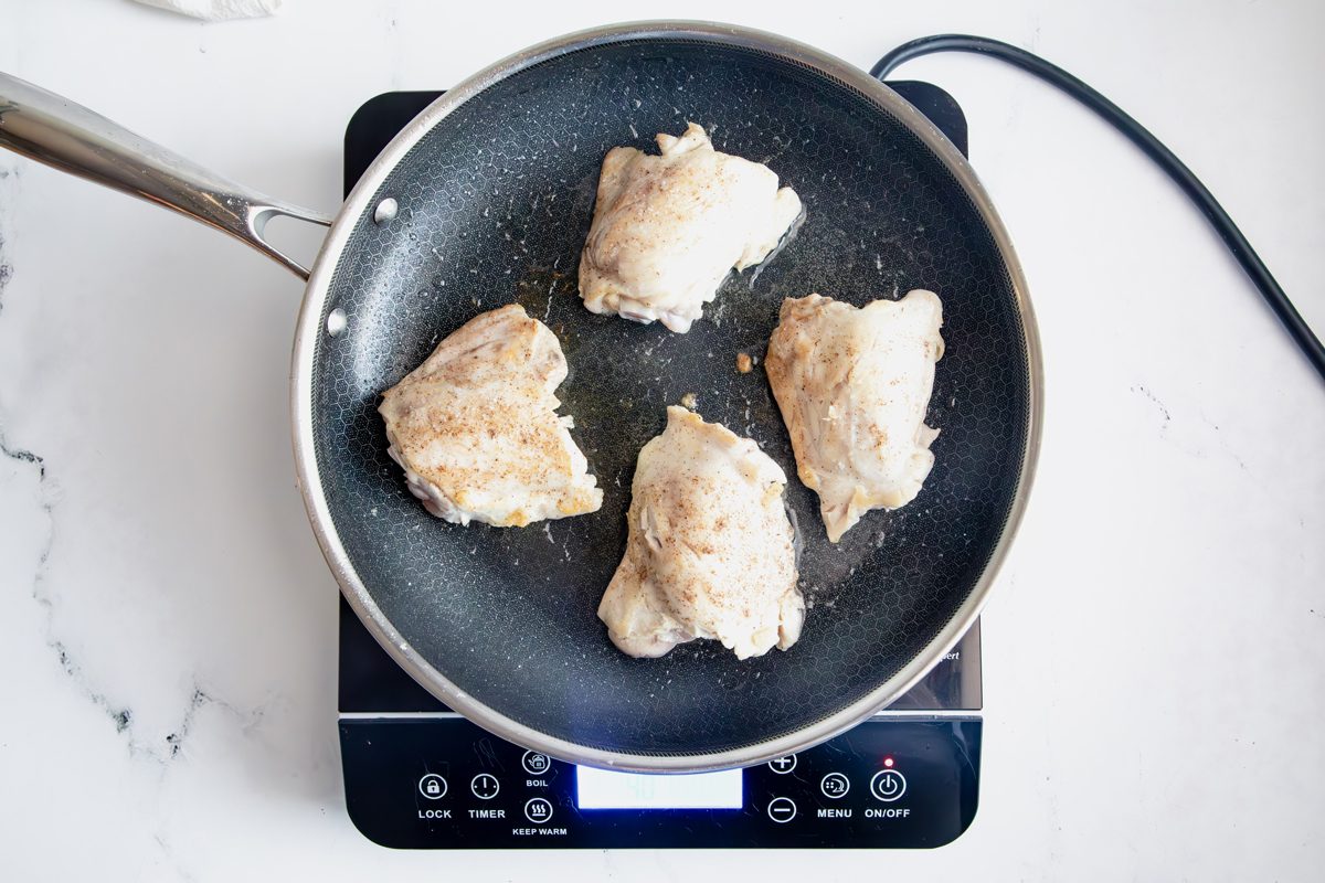 Overhead shot for Taste of Home Apple Chicken with chicken cooking on an induction cooktop.