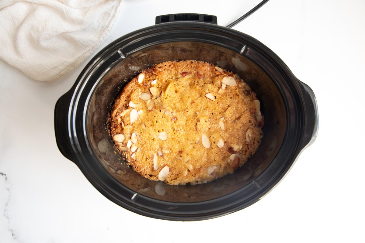 Overhead shot for Taste of Home Apple Streusel, apples topped with streusel mixture in a slow cooker after being baked.