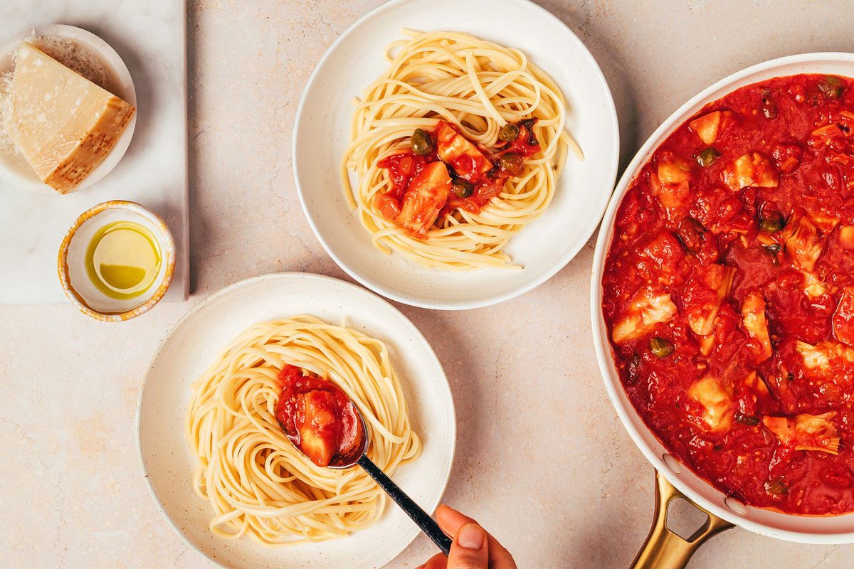 Combining cooked pasta with sauce to make the Artichoke Tomato Pasta recipe by Taste of Home