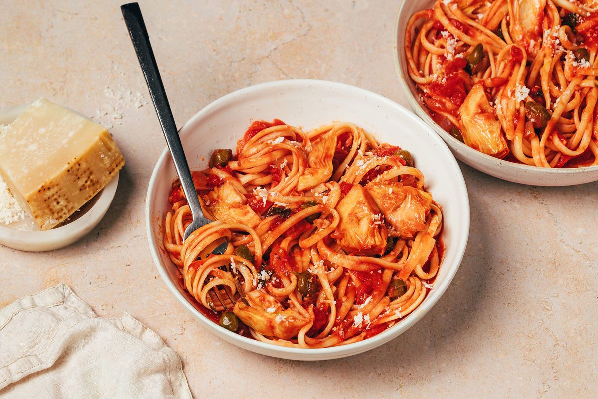 Two bowls with Artichoke Tomato Pasta topped with grated parmesan recipe by Taste of Home