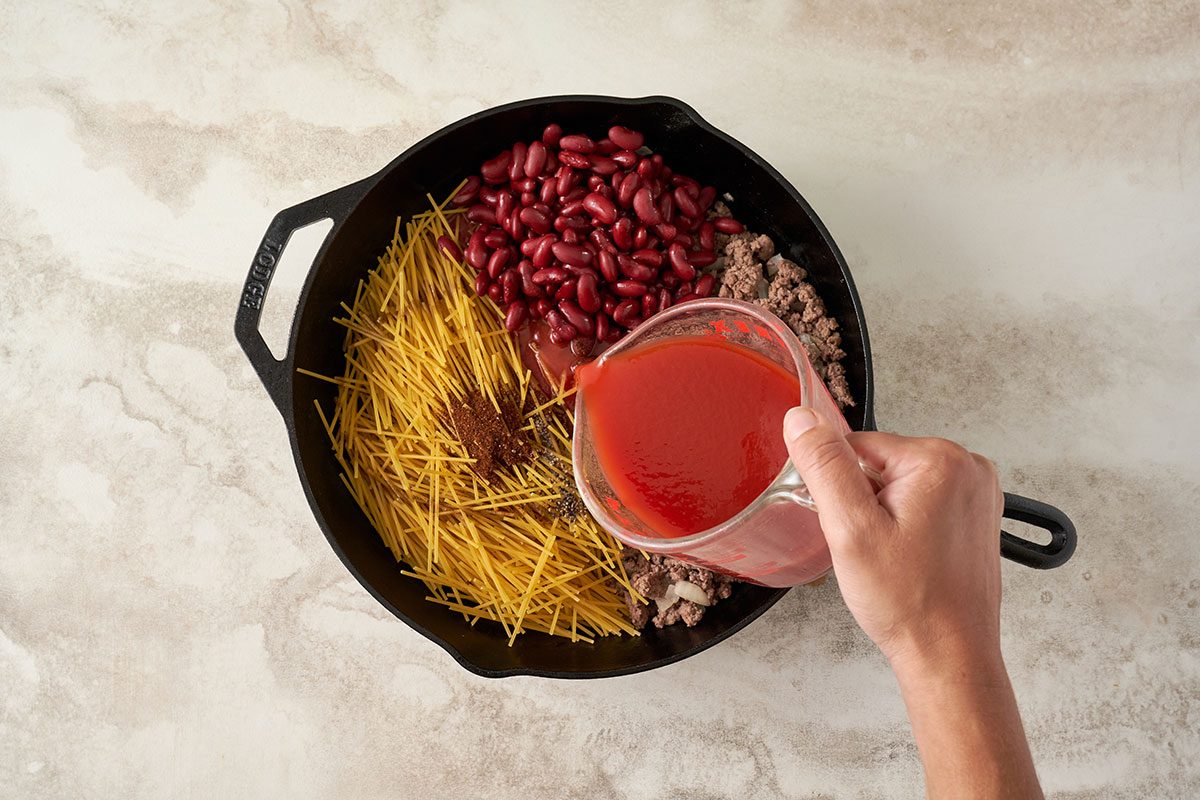 Drain excess liquid and transfer the beef mixture to a greased baking dish. Stir in tomato juice, kidney beans, broken spaghetti, Worcestershire sauce, and seasonings for this Baked Chili Spaghetti by Taste of Home.