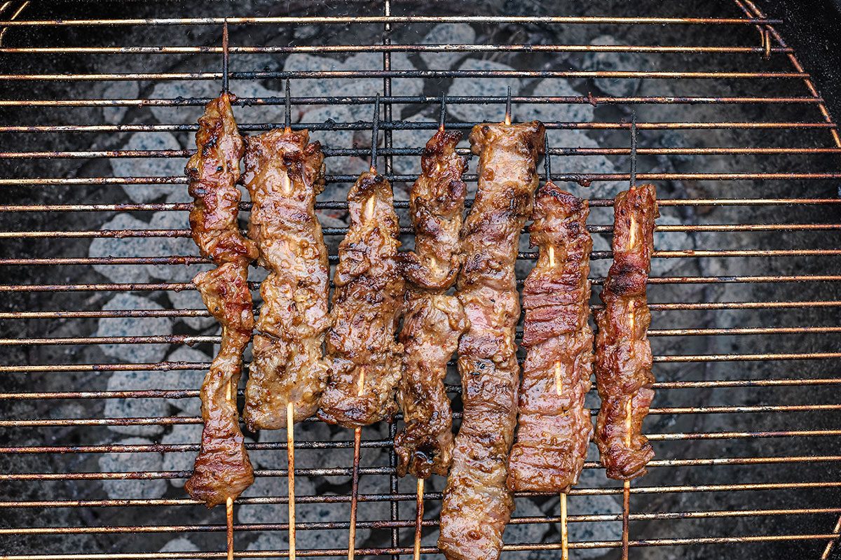 Grilling beef satay over charcoal.