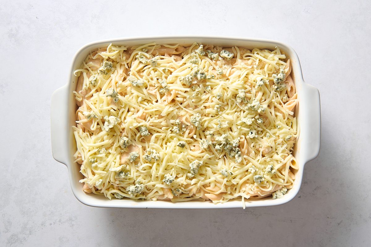 Casserole in a baking dish topped with shredded cheese ready for baking