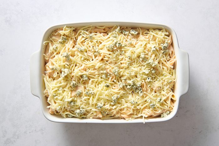 Casserole in a baking dish topped with shredded cheese ready for baking