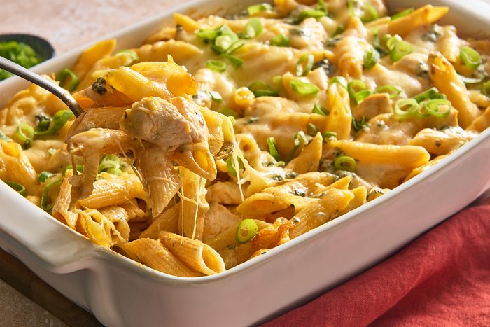 Closeup of a big spoonful of buffalo chicken casserole being scooped out of a baking dish