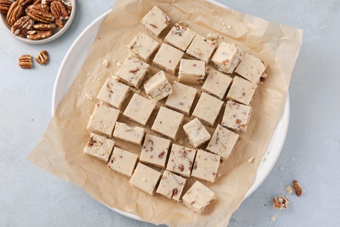 Butter pecan fudge ready and cut into 1 in squares, served on plate.