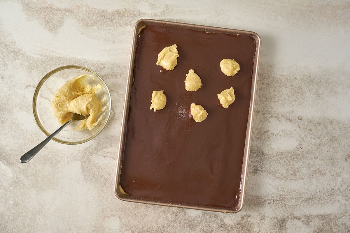 Taste of Home Cake Mix Bars: The final layer of cake mix topping is added over the chocolate filling before baking, showing scoops of cake mix being placed on top.
