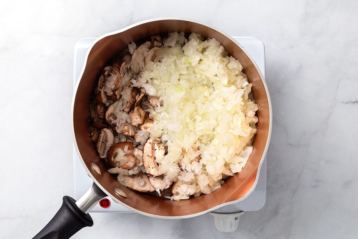 Sliced mushrooms and onion cooking in a saucepan for step two of Chicken Risotto recipe for Taste of Home