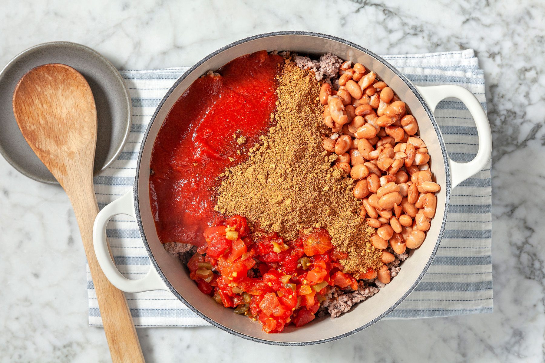 Tomato sauce, beans, tomatoes and chili mix added to the beef in the Dutch oven.