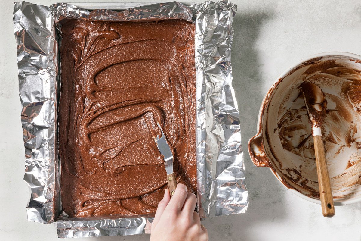 hand spreading batter Into the Prepared Pan.
