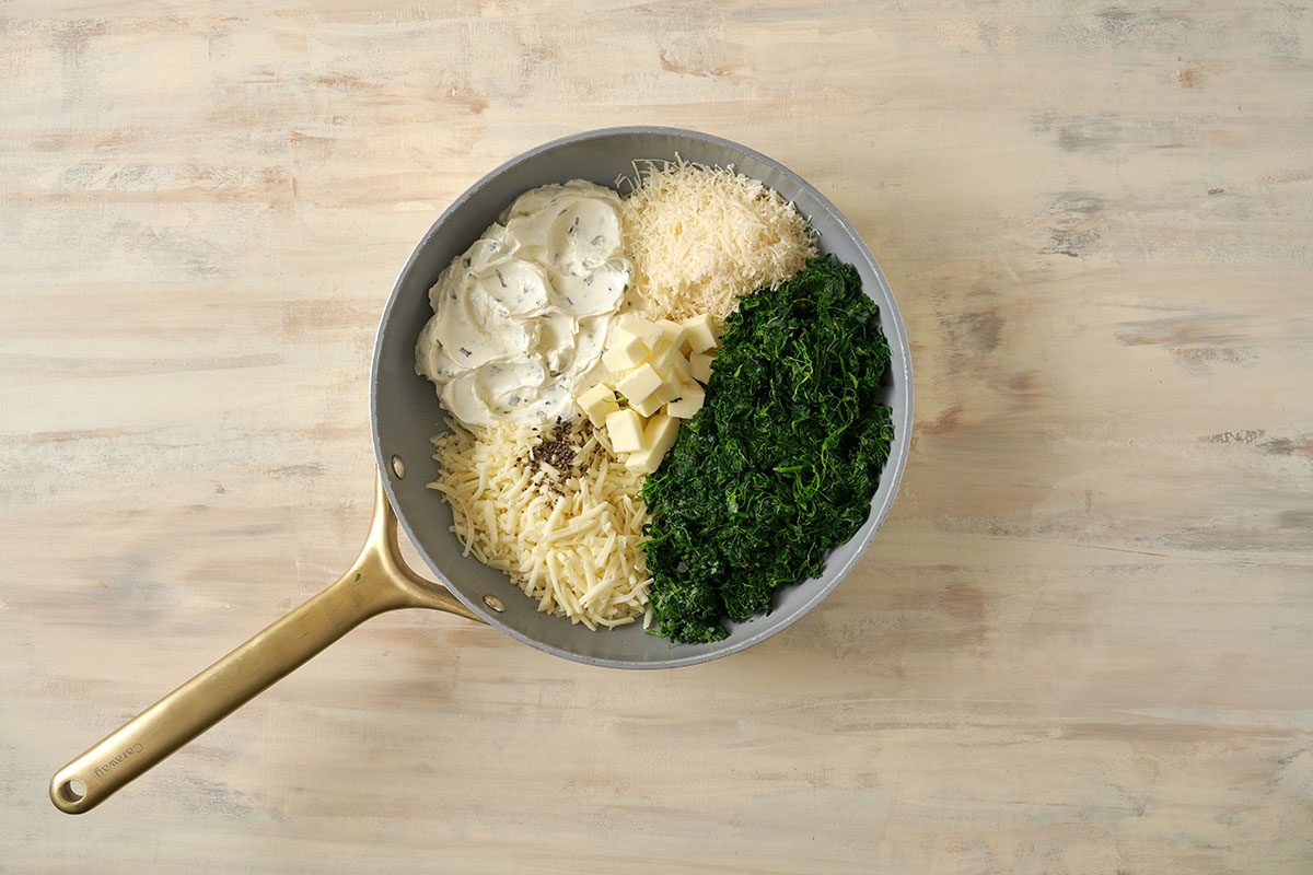Combining spinach, cream cheese, and other ingredients in a saucepan, cooking until blended and warm for the Creamed Spinach with Cream Cheese recipe, by Taste of Home.