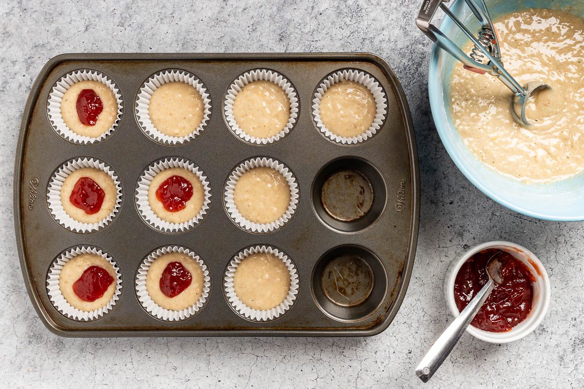 filling the muffin cups half way with batter, then adding the jam.