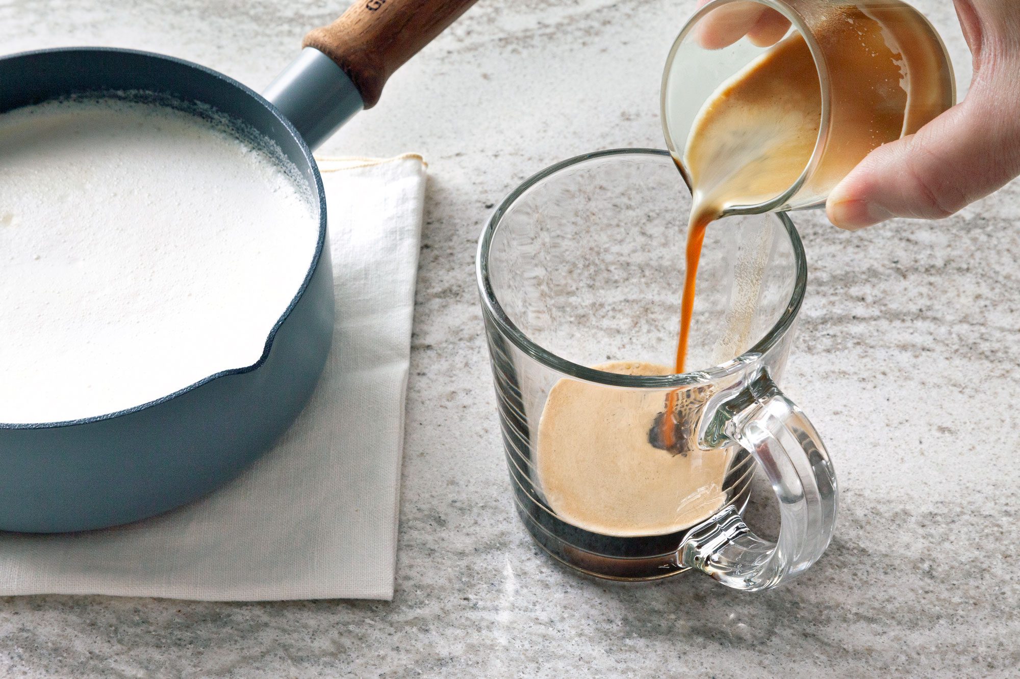 Pouring coffee from a glass carafe into a clear glass mug