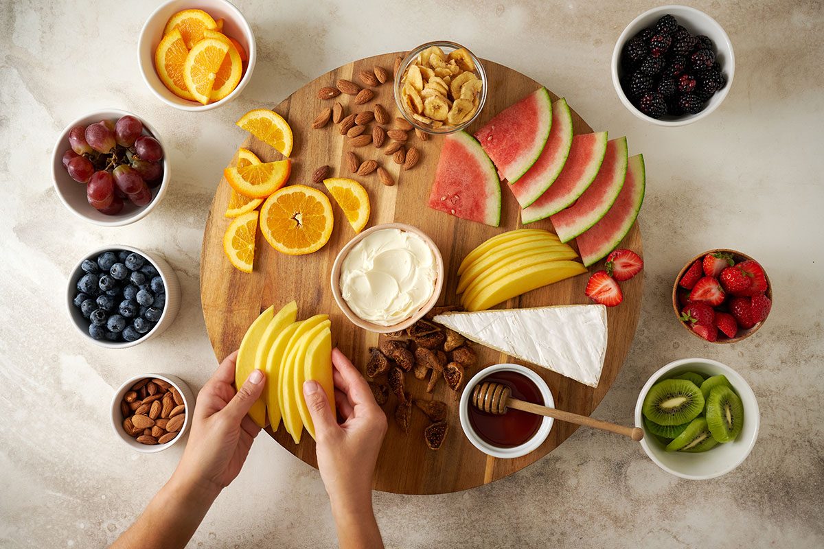 On a large platter or cutting board, arrange halved strawberries, figs, orange slices, grapes, mango, blueberries, blackberries, dried banana chips, kiwi slices, watermelon slices, almonds, Brie, and mascarpone cheese. Tuck a jar of honey among the fruit for the Fruit and Cheese Platter recipe, by Taste of Home.