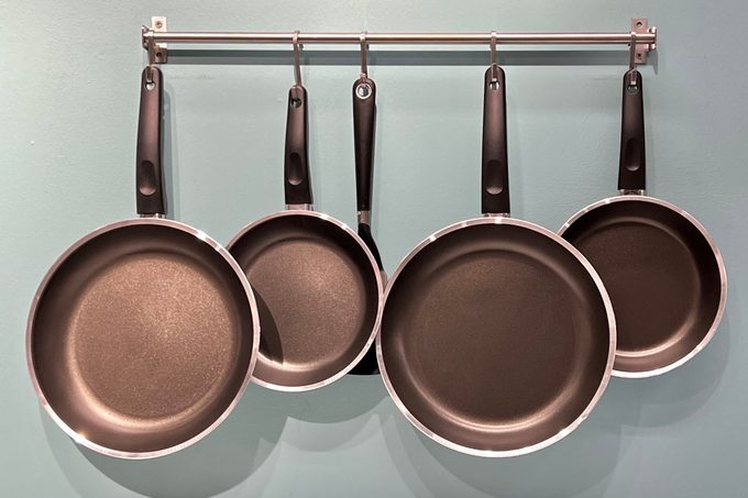 Set of kitchen metallic pans hanging on a pot rack in the kitchen