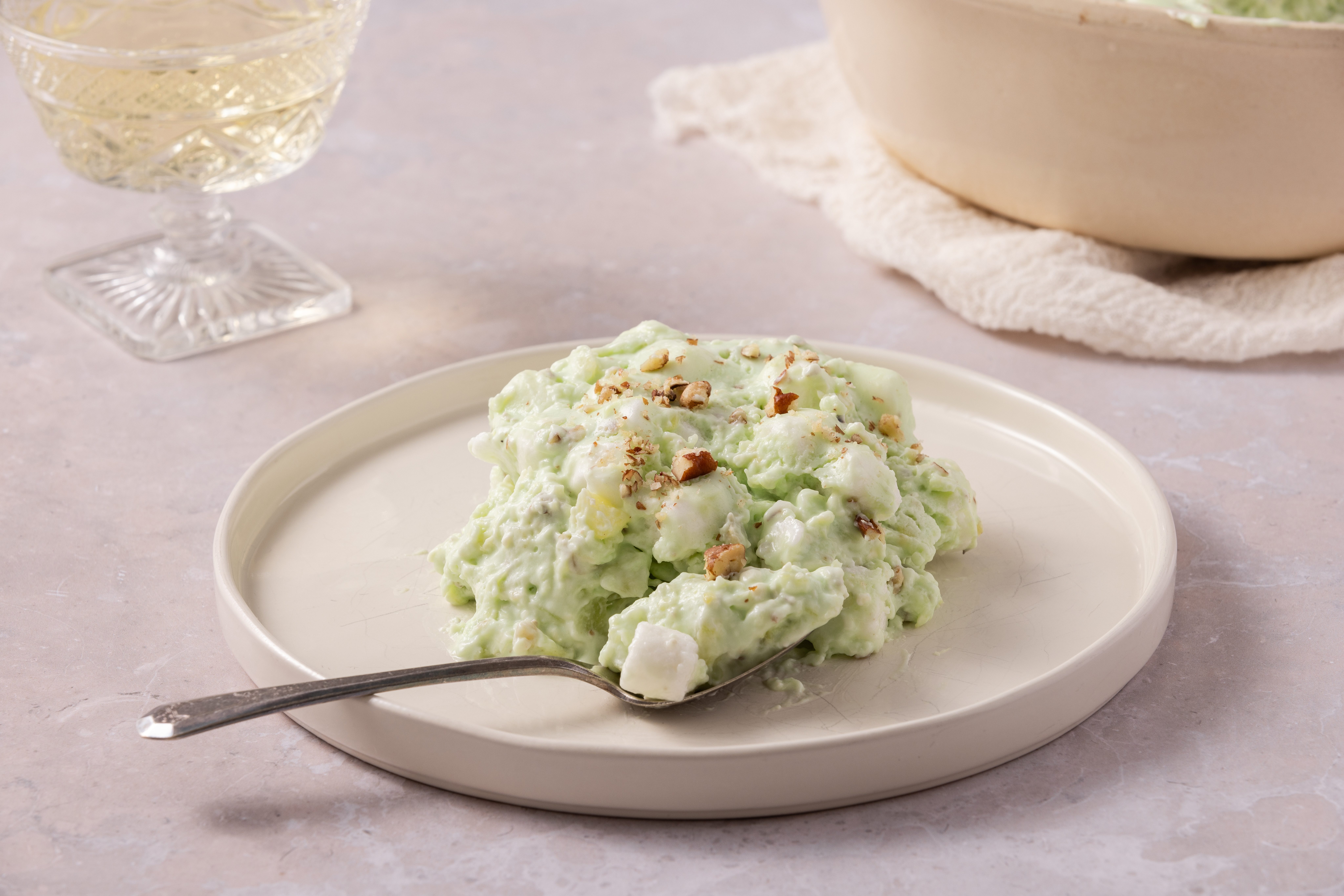 Green jell-o salad served on plate with a spoon full.