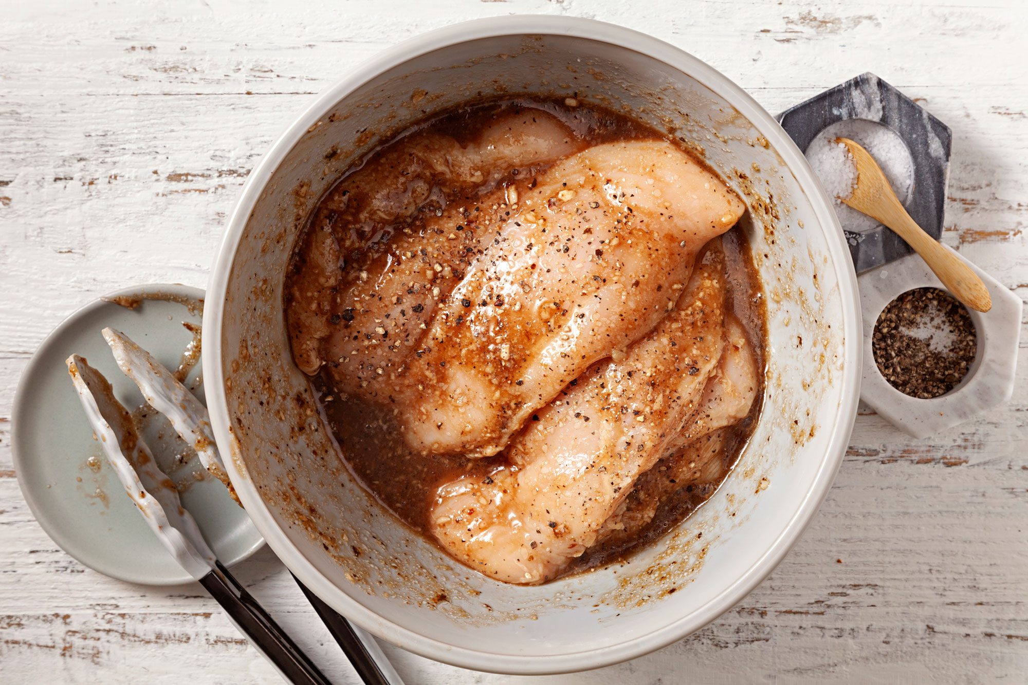 In a large bowl, combine vinaigrette and garlic then add chicken and turn to coat with tong