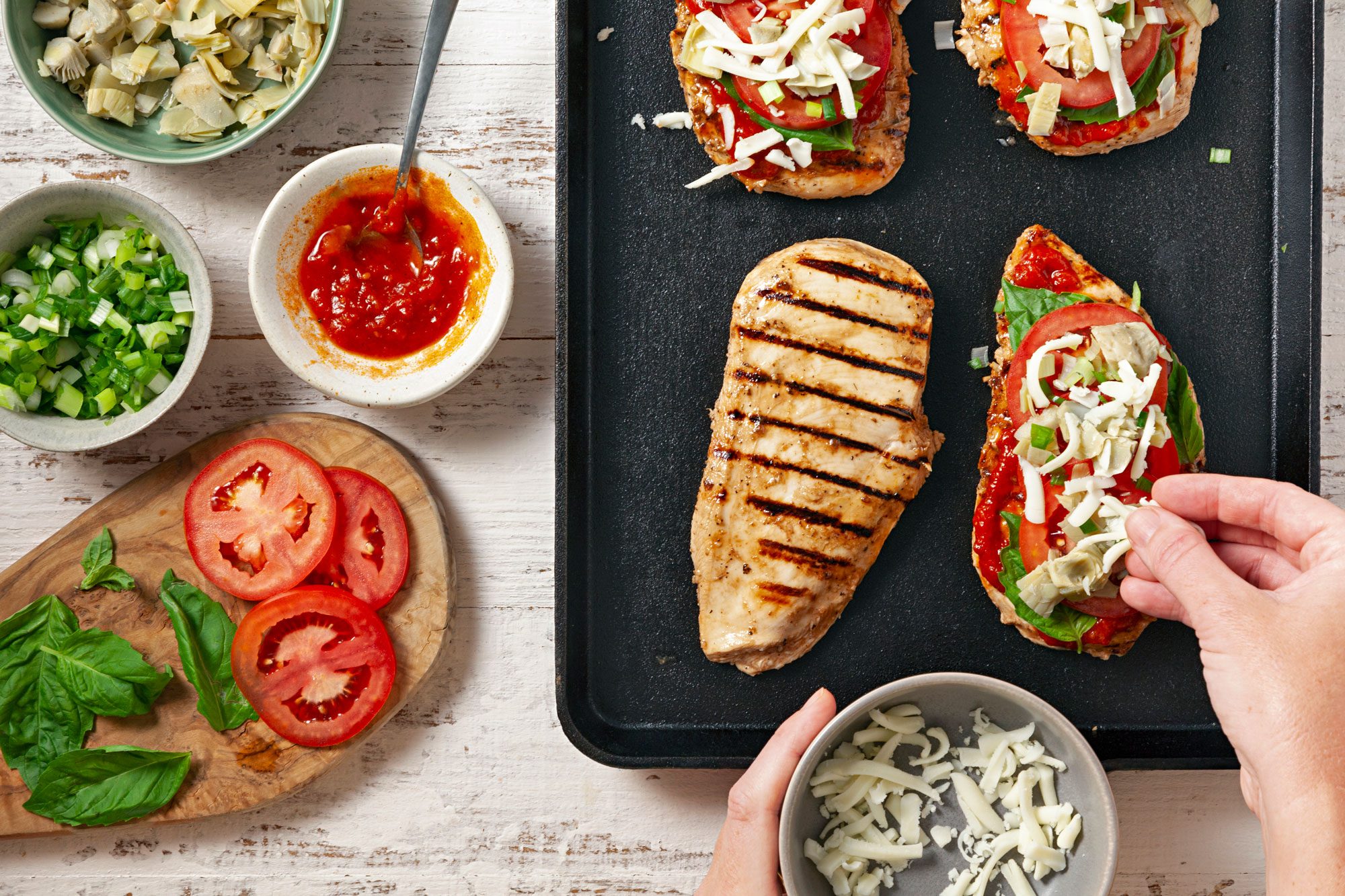 Top with marinara, basil, tomatoes, artichokes, onions and cheese