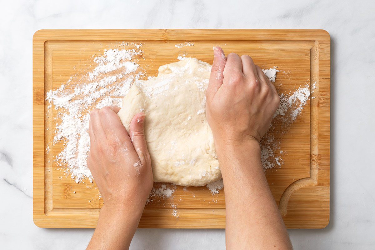 Kneading bread dough on floured wooden cutting board for step three of Homemade Breadsticks for Taste of Home