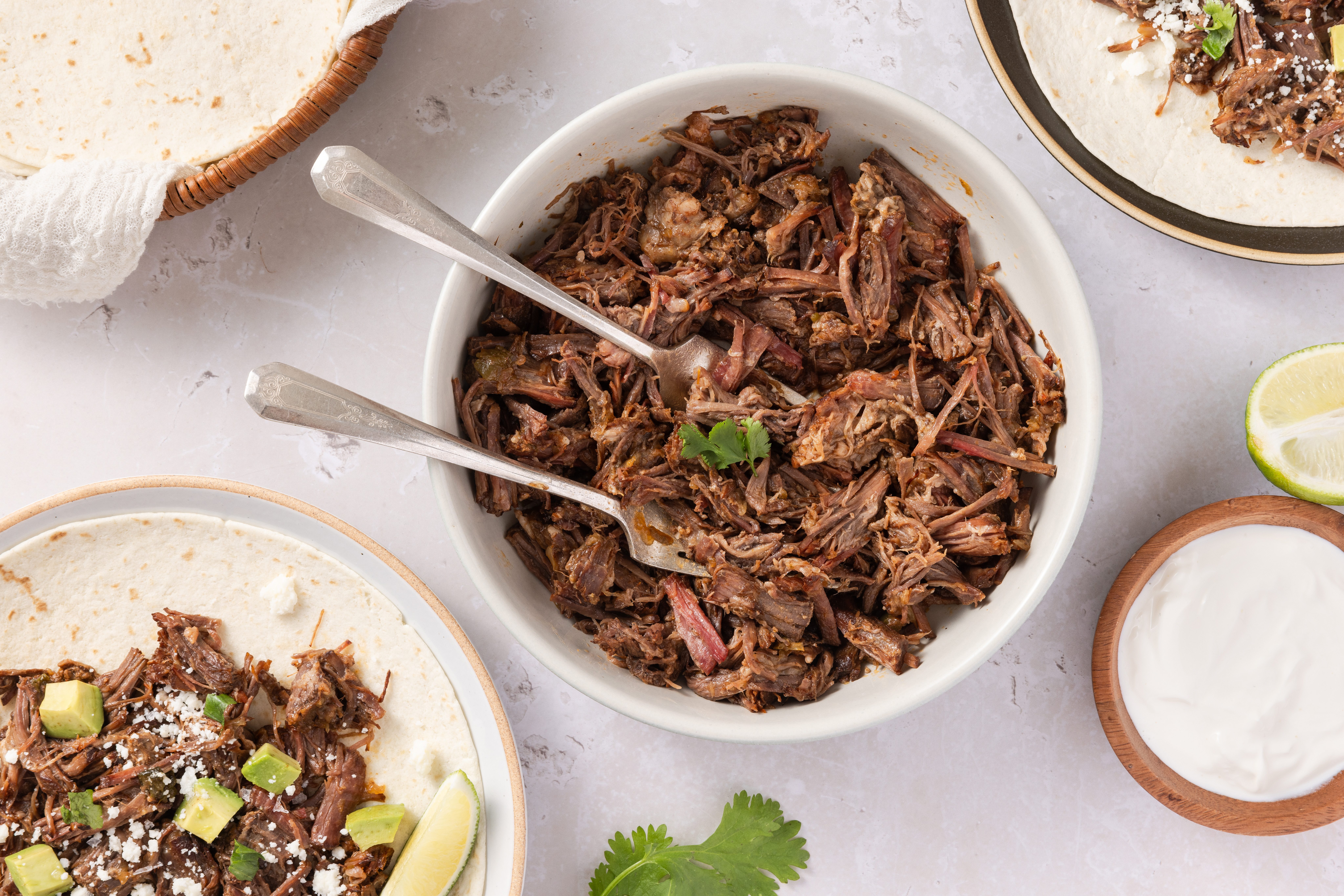Instant pot beef carnitas shredded in bowl with forks ready to serve.