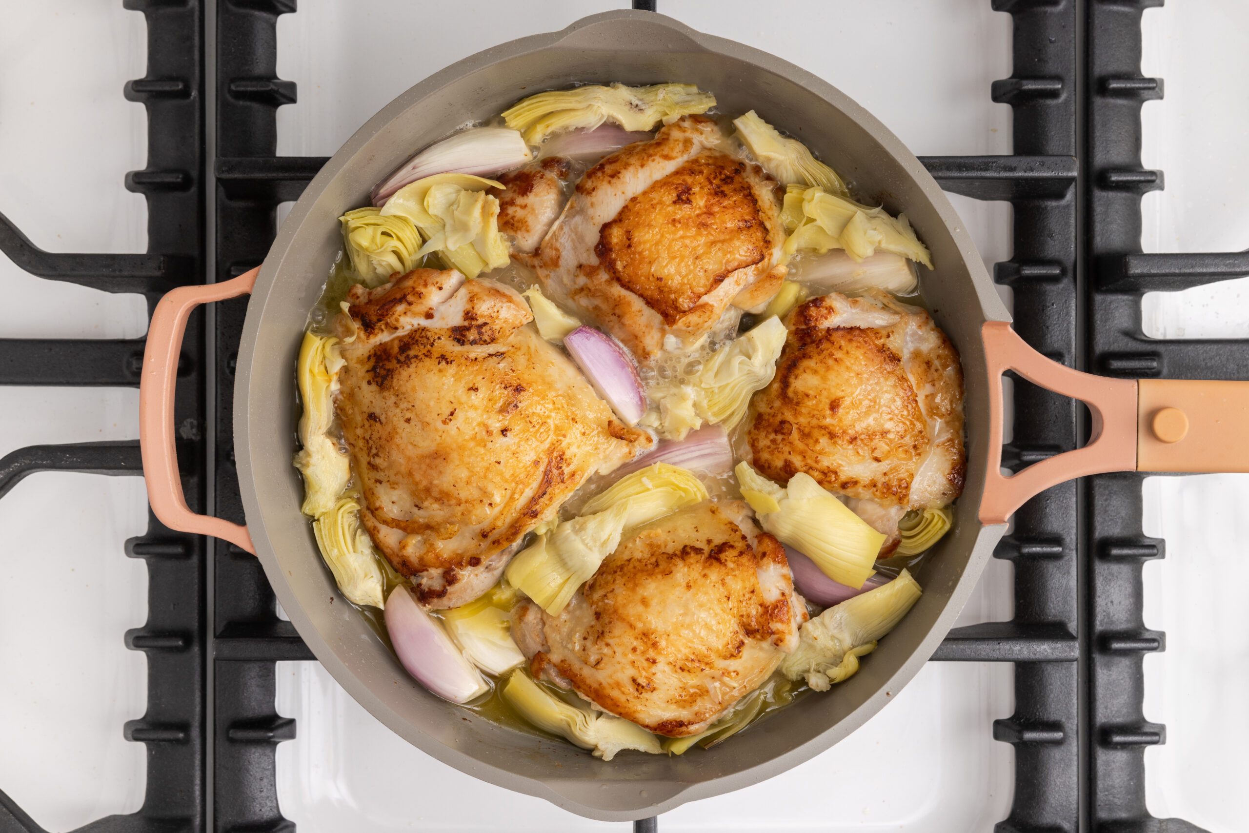 Shallots, artichoke hearts and white wine added to the skillet with cooked chicken.