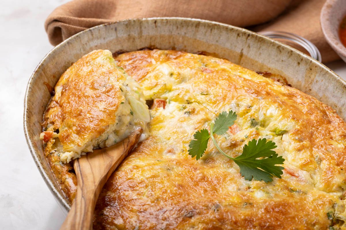 Mexican Breakfast Casserole in a baking dish with wooden spoon on marble table