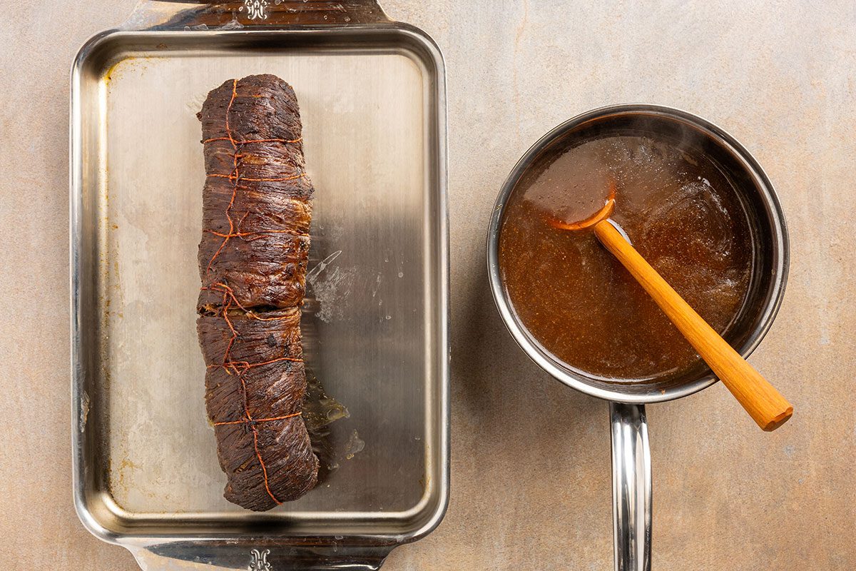 rolled and cooked flank steak with side of sauce.