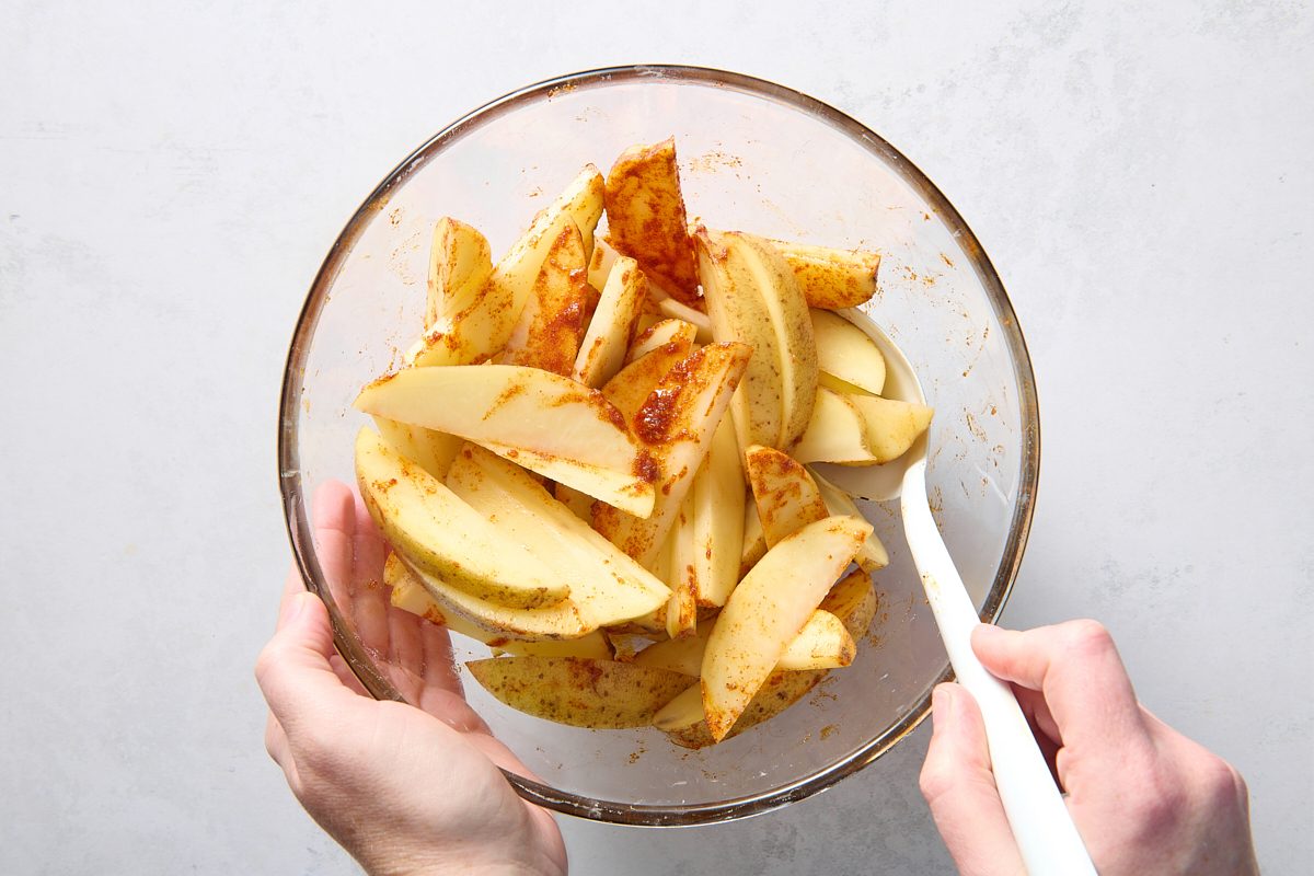 Tossing the potato wedges in seasoning
