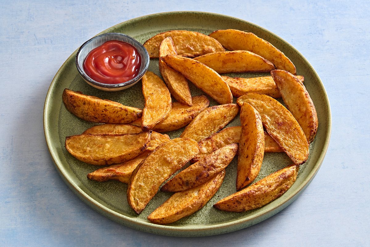 Shot of a plate full of oven fries with a side of ketchup