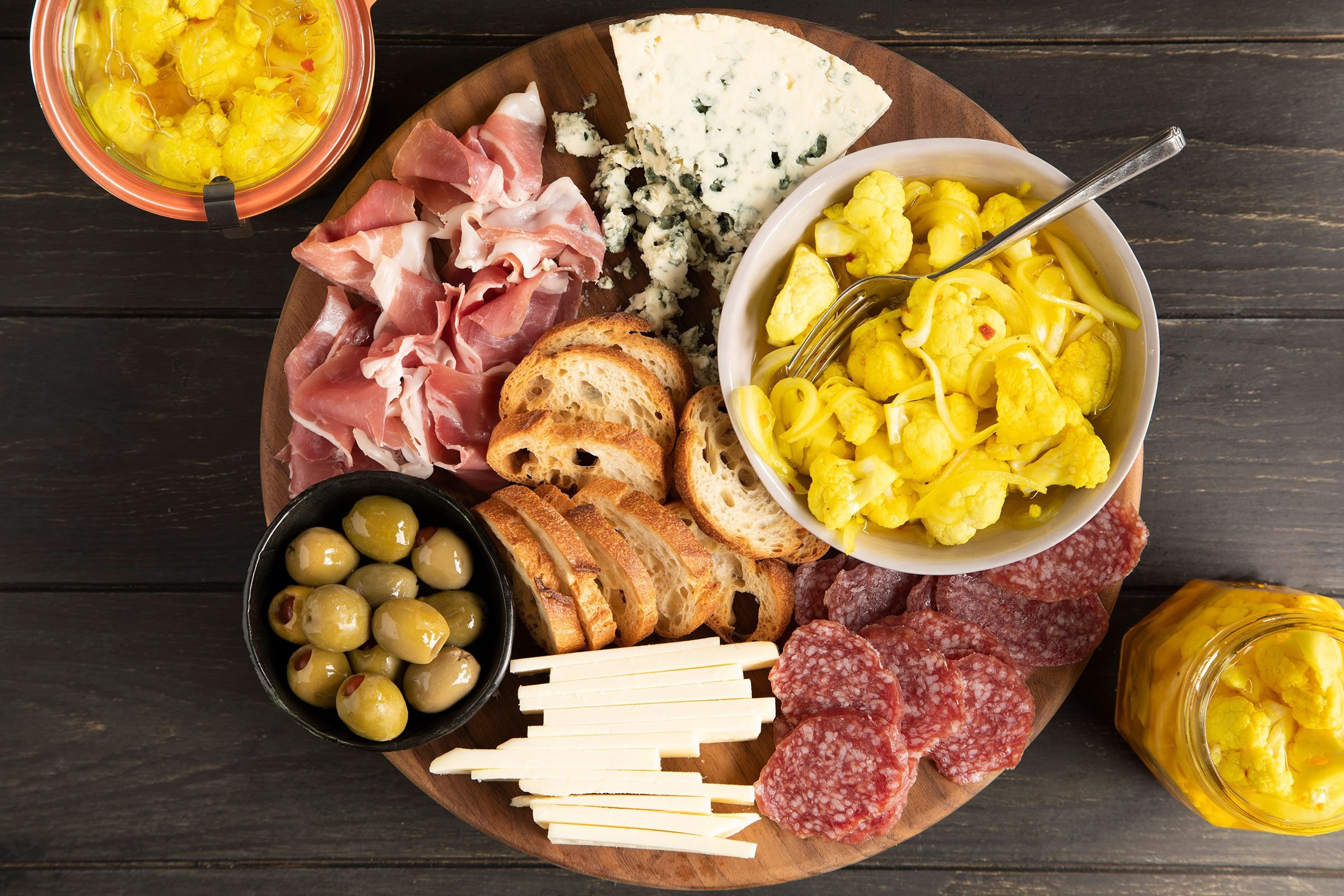 Pickled Cauliflower with bacon, cheese and bread on a board