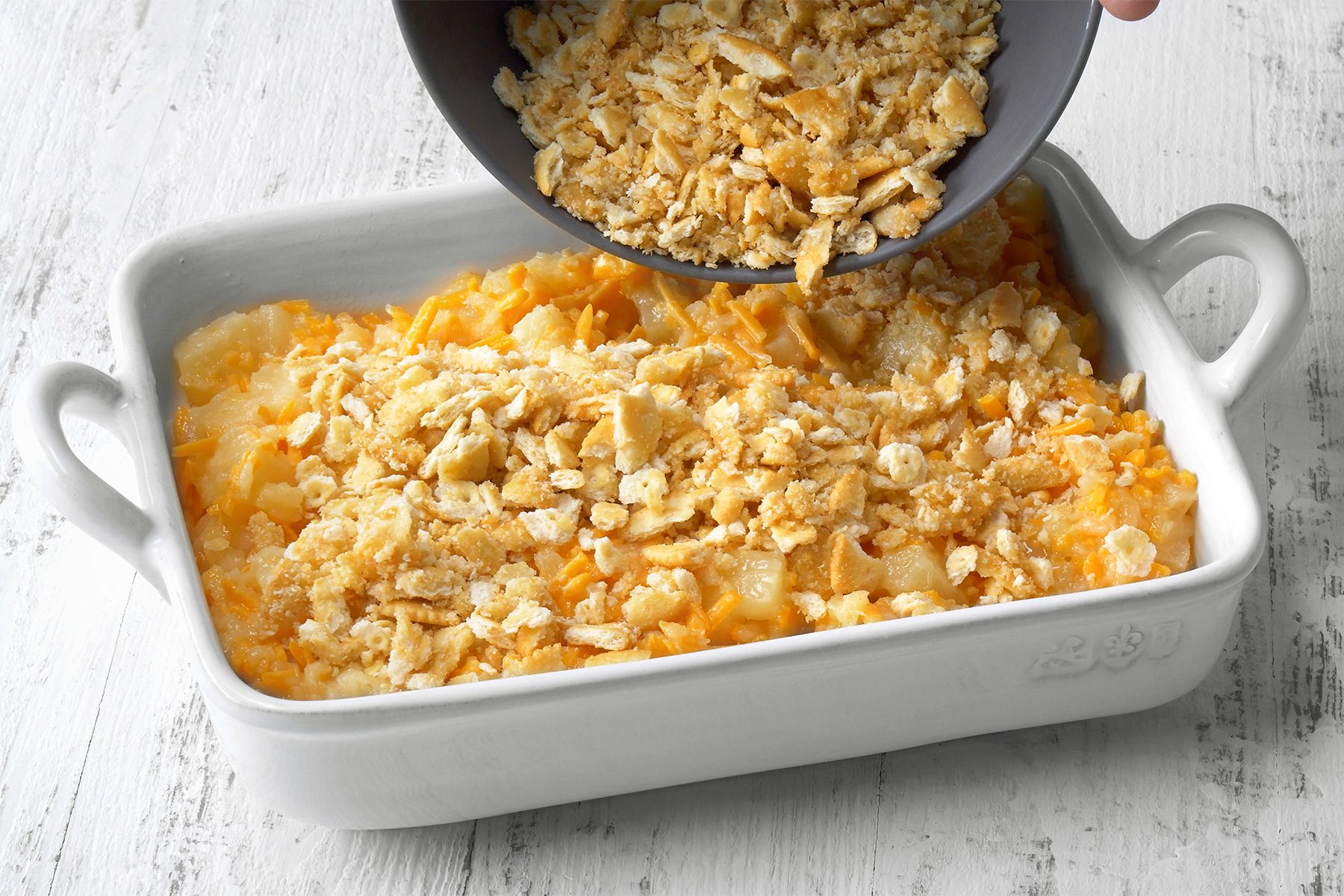 3/4th shot of Transferring batter to a greased baking dish over white wooden background