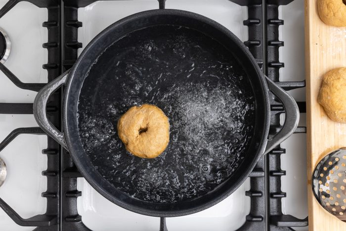 Bagels being boiled in dutch oven.