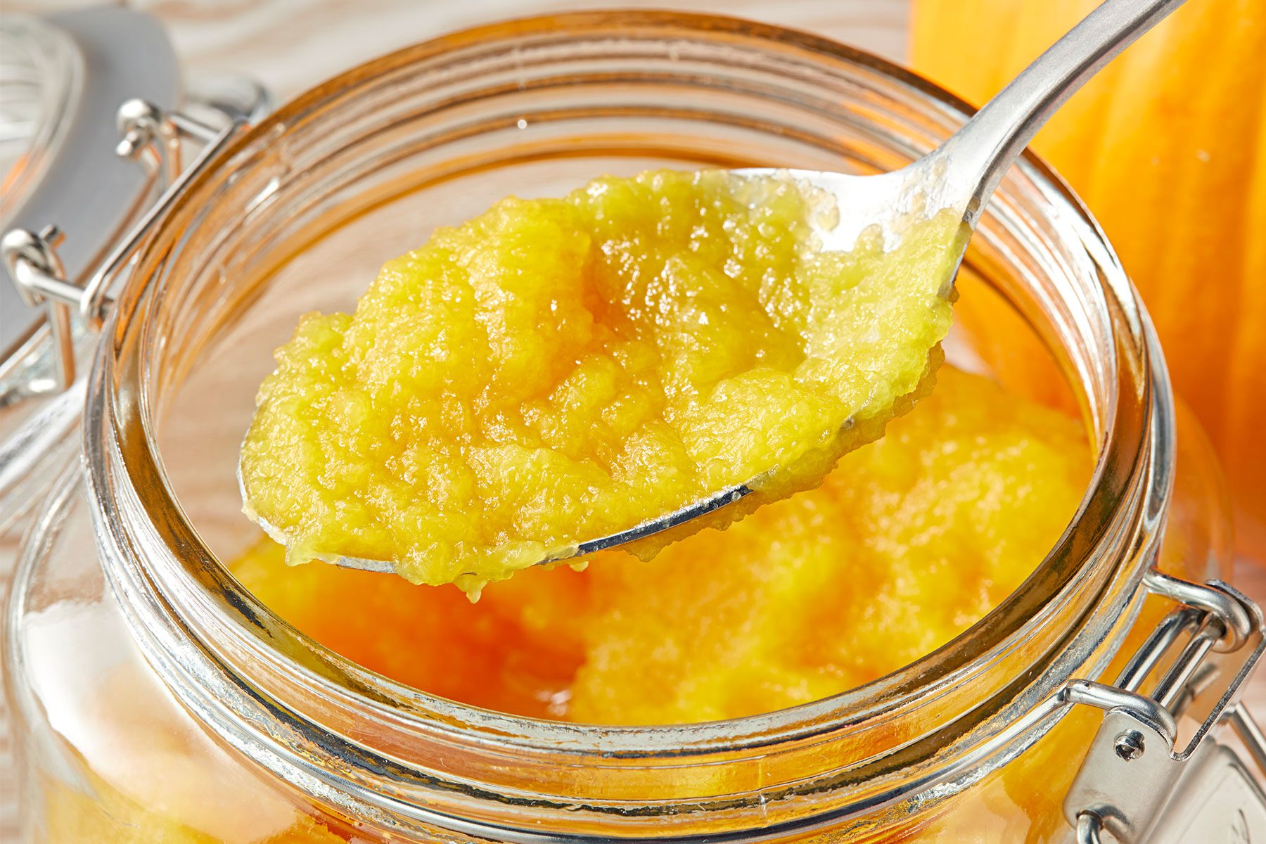 Spoonful of pumpkin puree over an open glass jar.