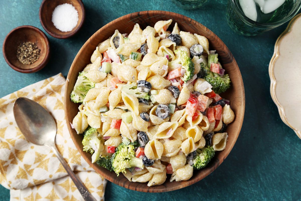 Close up of Taste of Home's Creamy Pasta Salad served on plates on a green surface.
