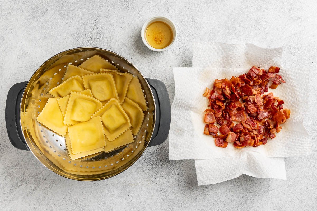 cooked ravioli and bacon with a side of bacon drippings.