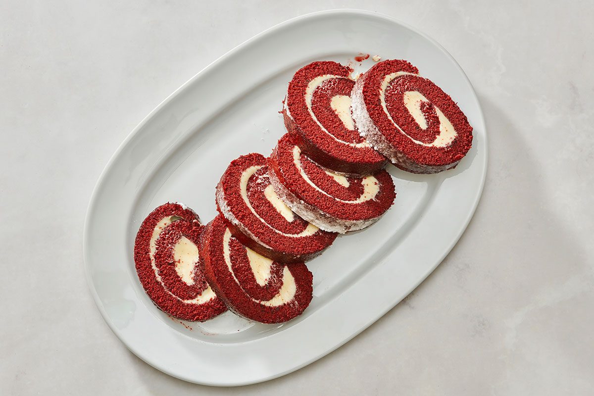 Red velvet cake roll served on a platter with a slice removed