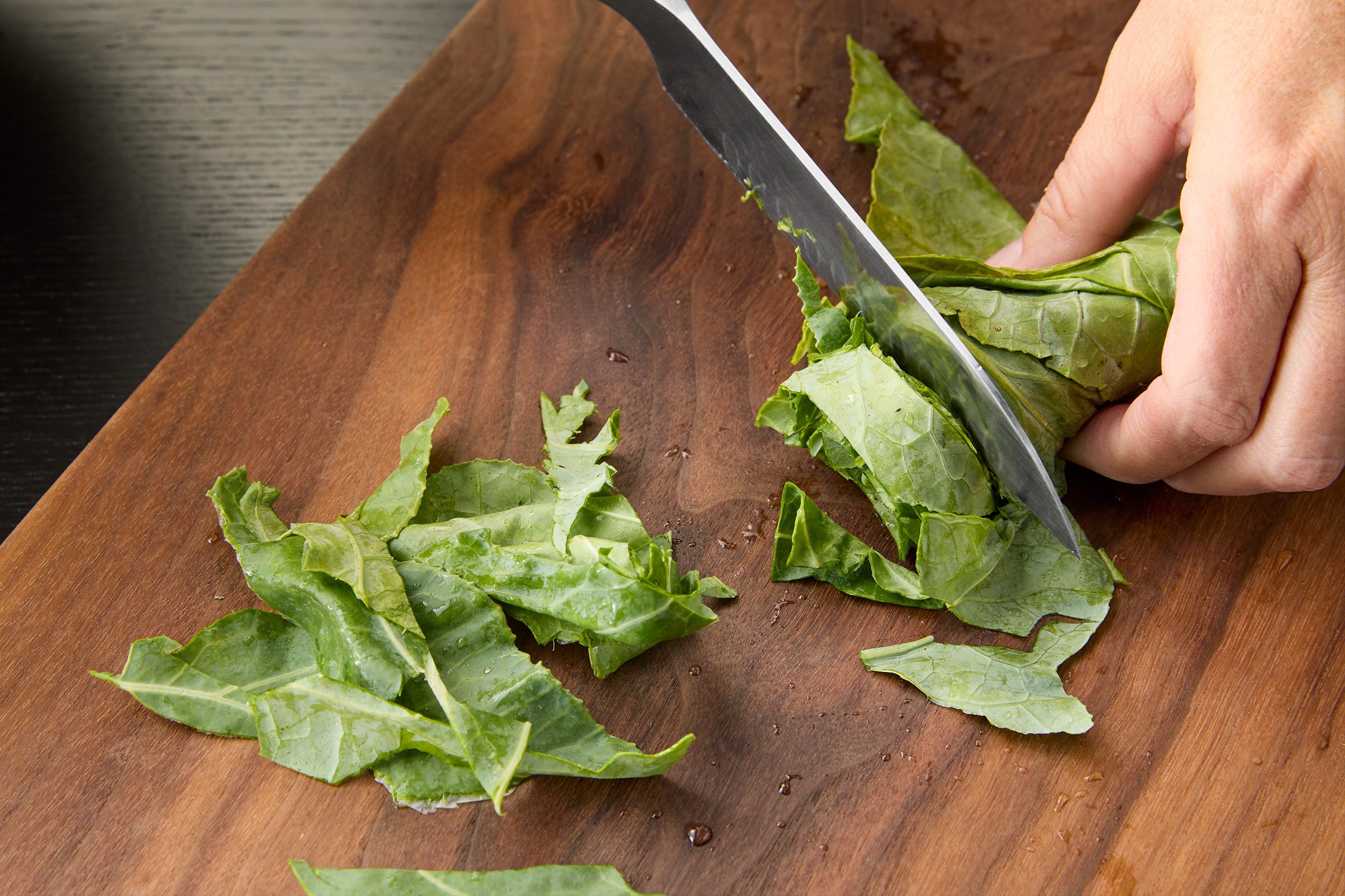 rolling collard leaves up tightly and slicing them 