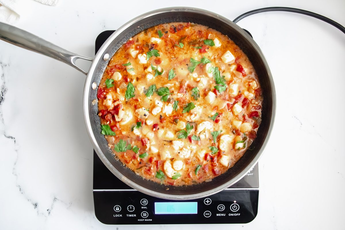 Overhead shot for Taste of Home Seafood Linguine, sauce and seafood cooking in a Hexclad over an induction cooktop.