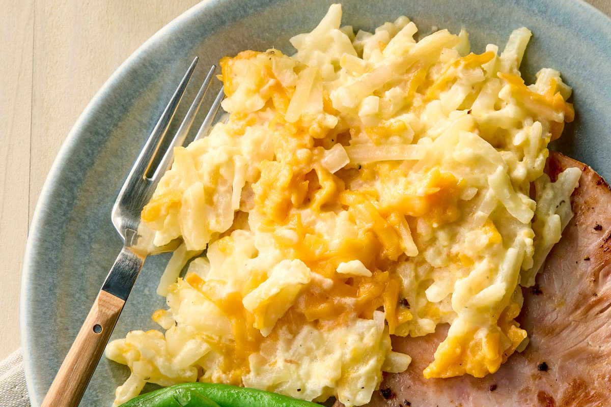 Close Up Shot Of Crockpot Cheesy Potatoes on a plate with a fork