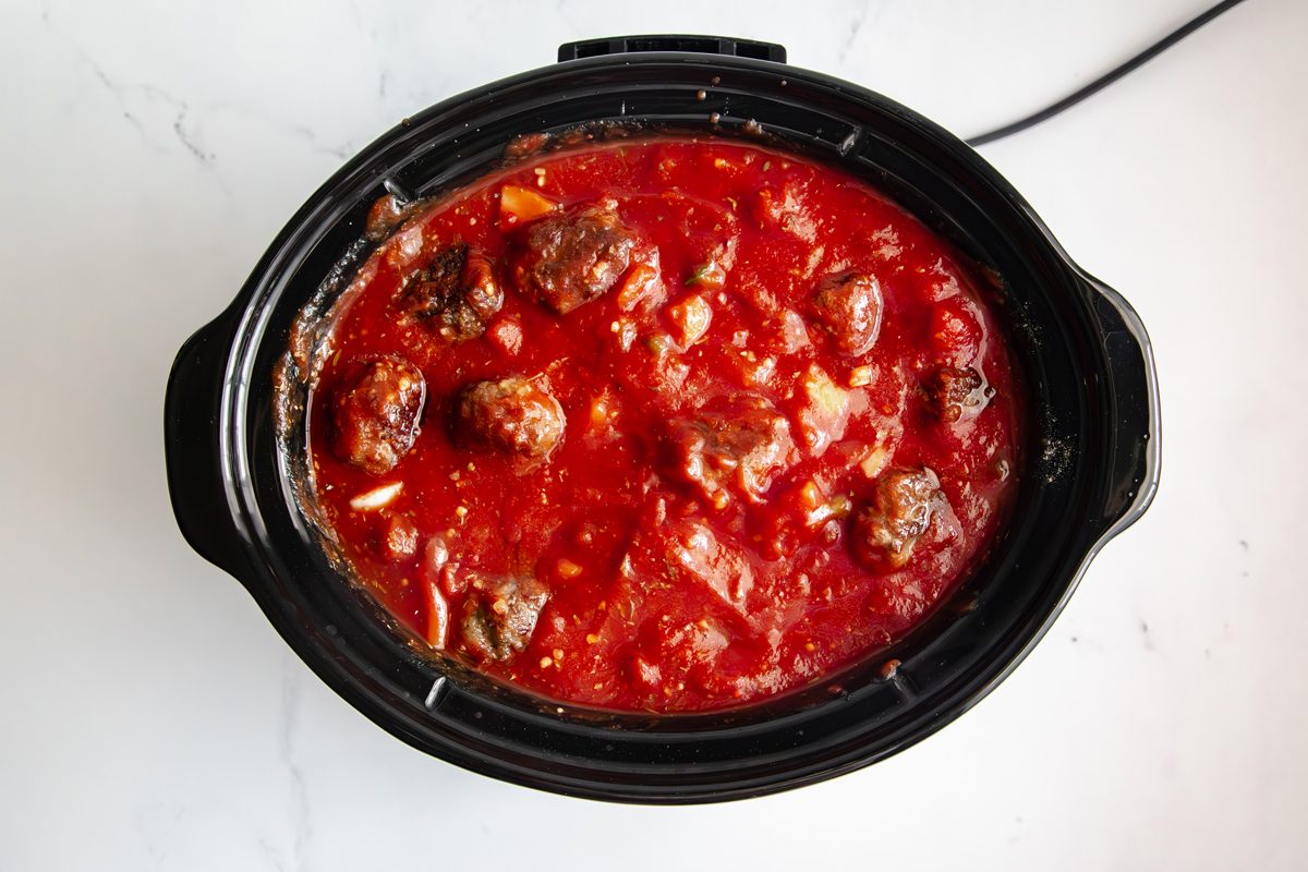 Overhead shot for Taste of Slow-Cooker Spaghetti and Meatballs, meatballs and sauce in a slow cooker before being cooked.