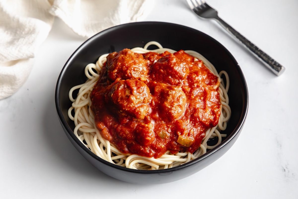 Beauty shot for Taste of Slow-Cooker Spaghetti and Meatballs being served in a black bowl.