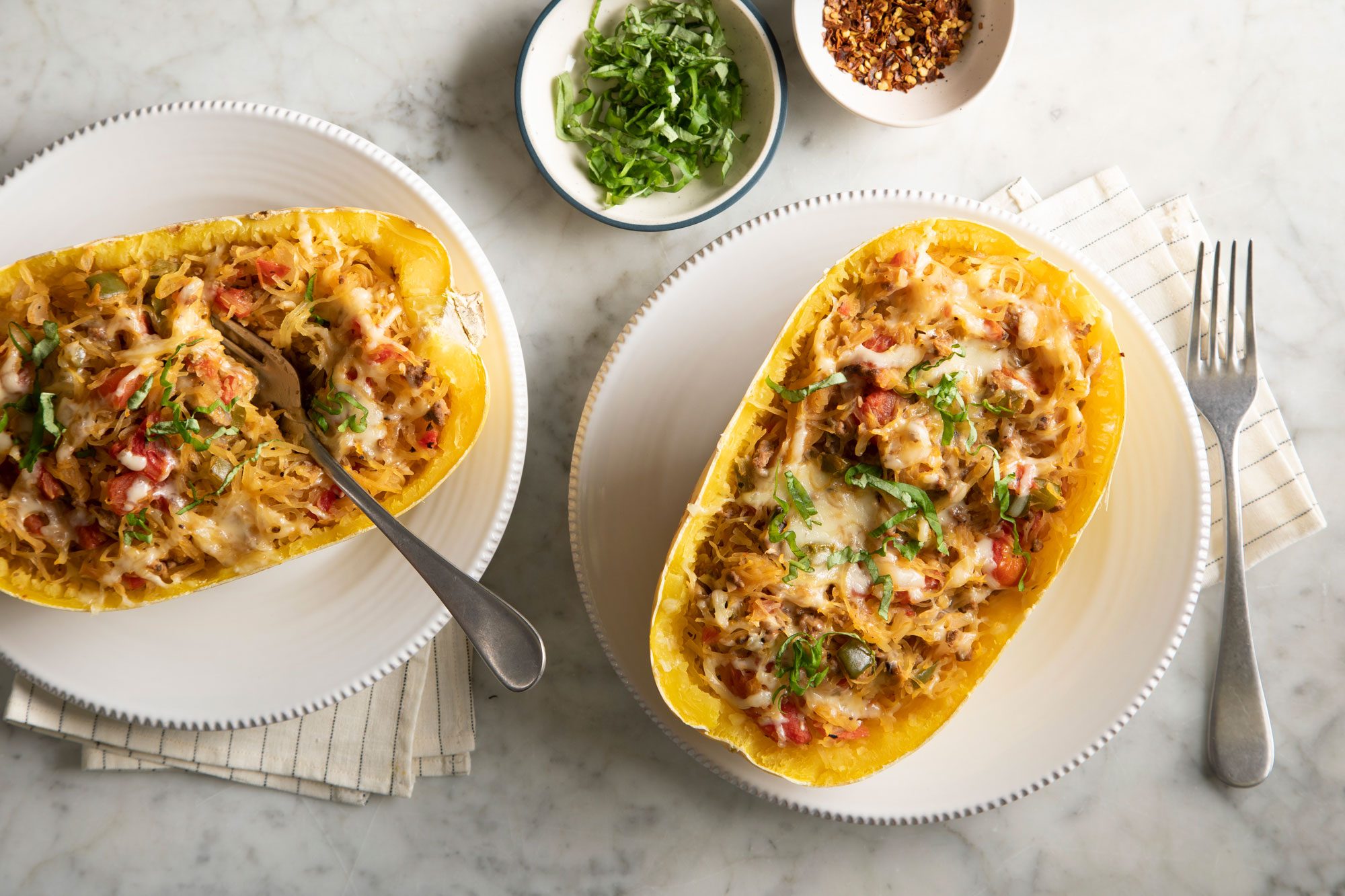 Overhead shot of Spaghetti Squash Boats served on white plates; marble surface;