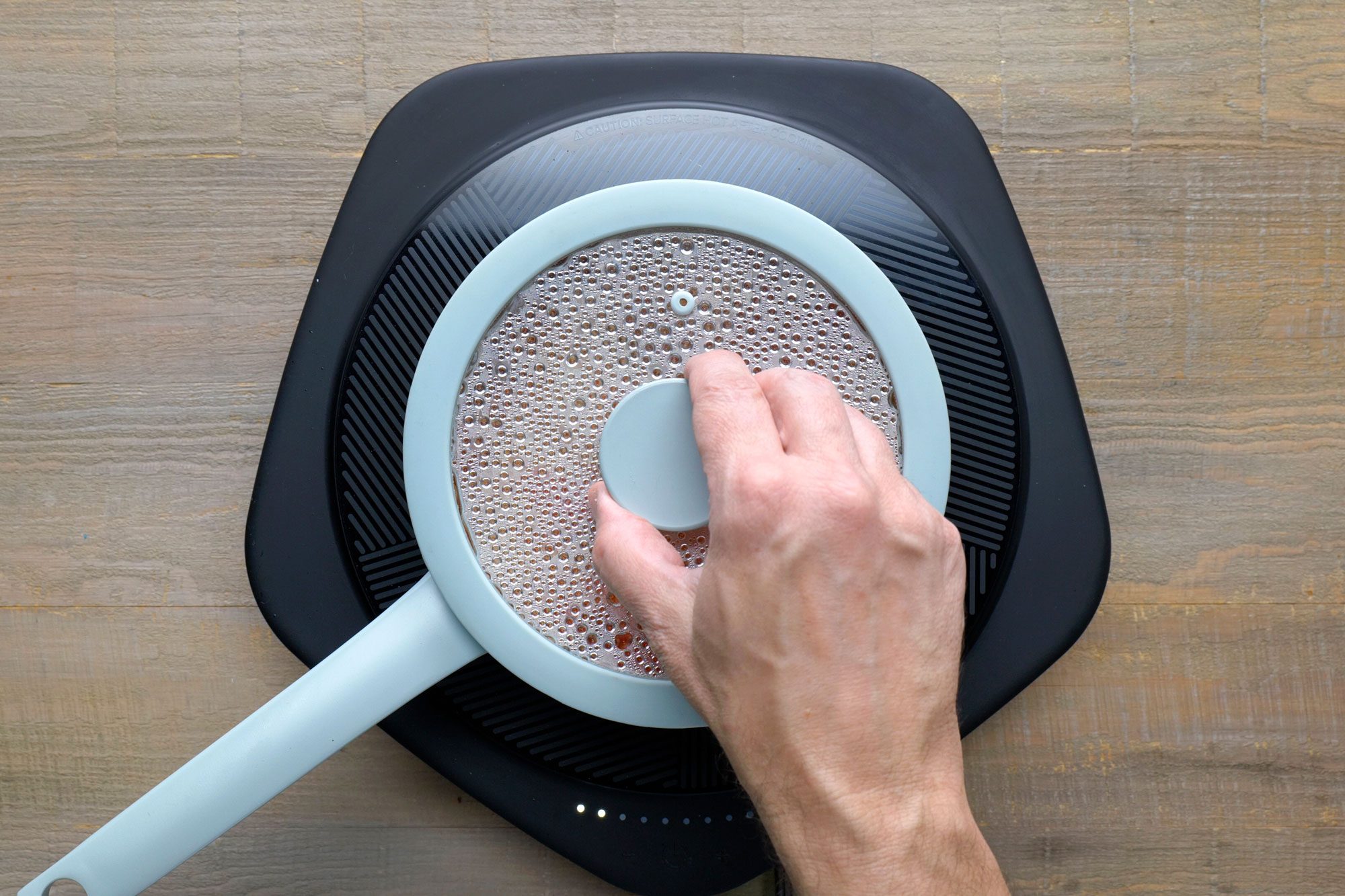 Lifting the lid off a saucepan on an electric induction cooktop