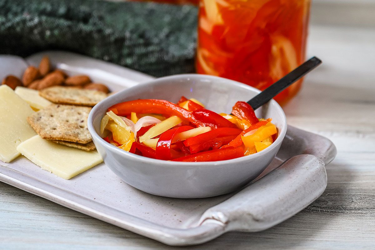 Sweet pickled peppers served with assorted crackers and cheese as a snack.