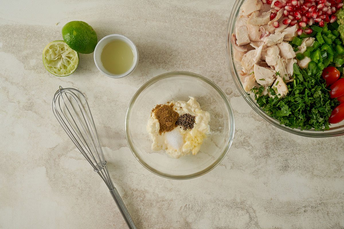 Overhead view of mayonnaise, lime juice, minced garlic, cumin, salt, and pepper being whisked together in a small bowl for the dressing in the Taste of Home Avocado Chicken Salad recipe.