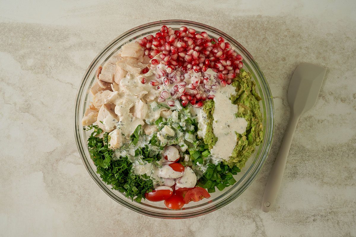 Overhead view of the dressing being poured over the chicken and avocado mixture, ready to be gently tossed for the Taste of Home Avocado Chicken Salad recipe.